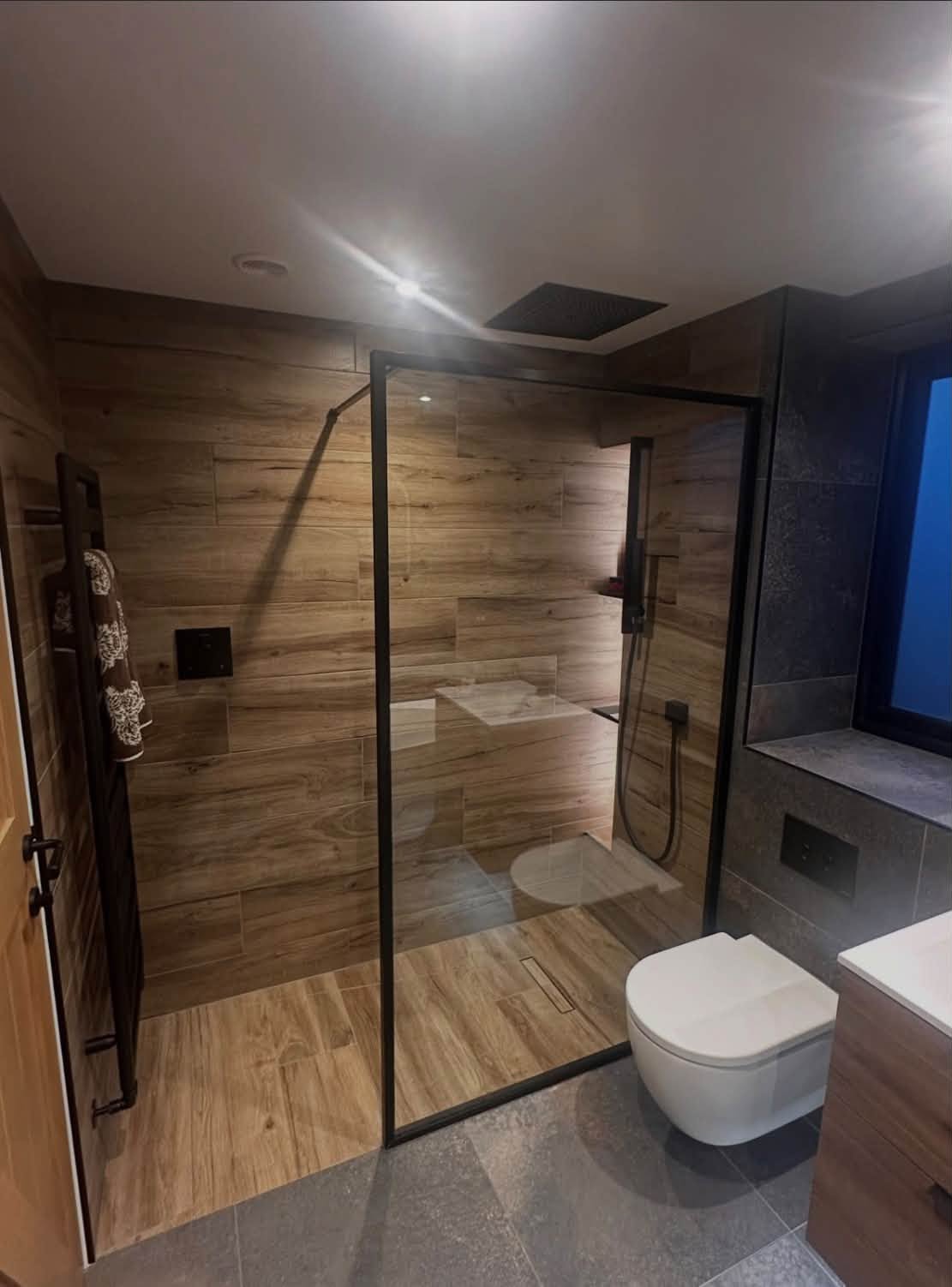 Completed bathroom with walk-in shower, wood-effect tiles and wall-mounted fittings
