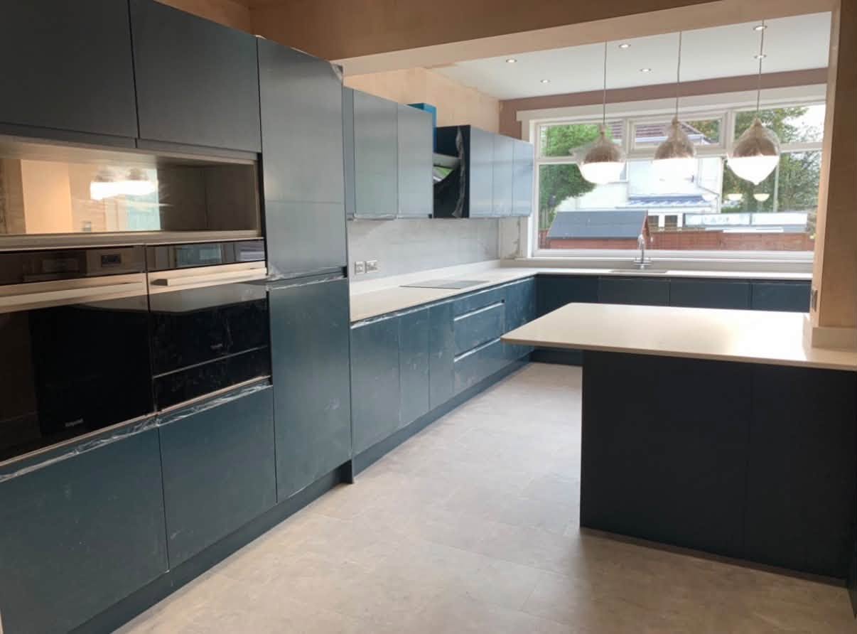Completed deep-blue kitchen with pale worktops and a peninsula
